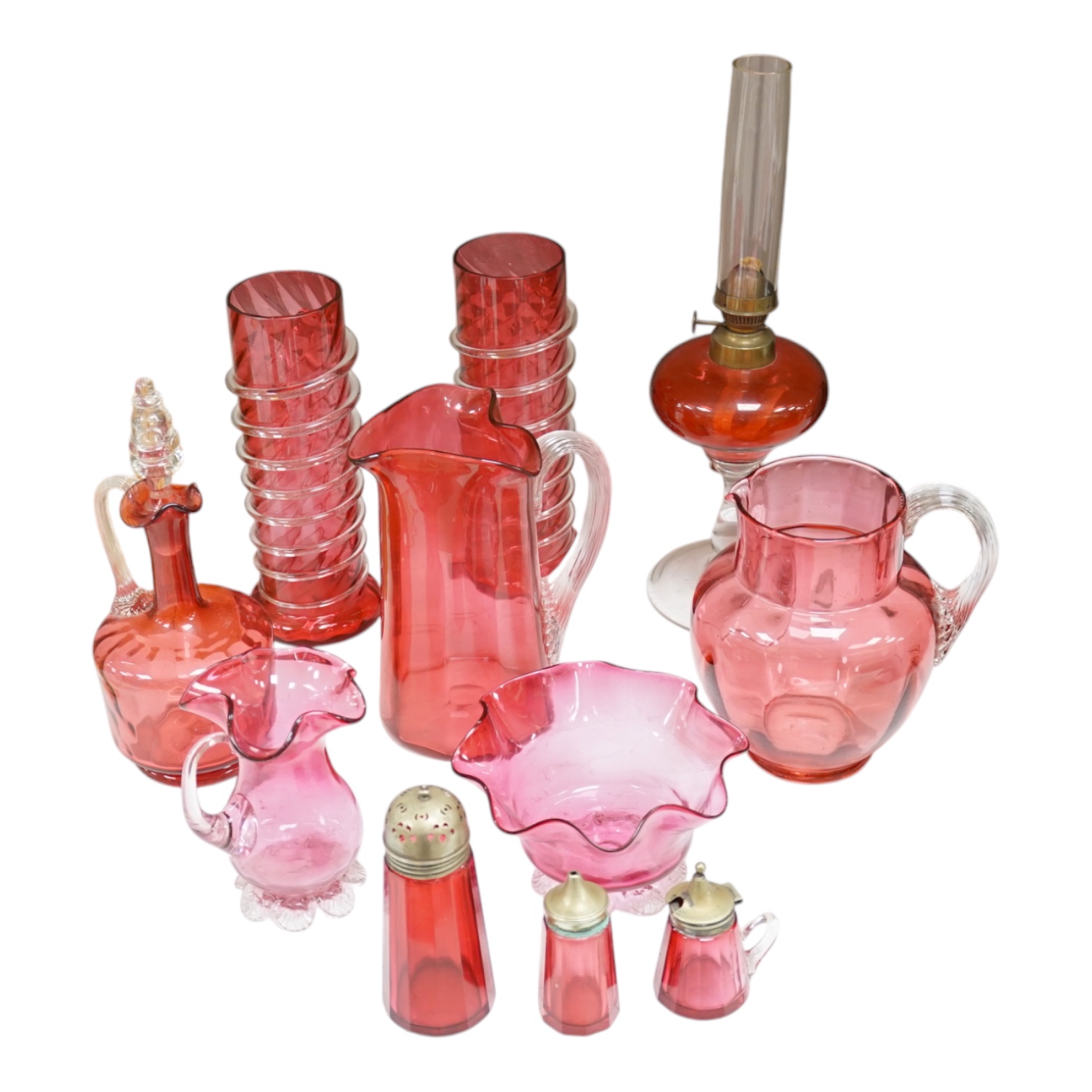 A quantity of cranberry glassware to include pair of vases with trailed decoration, jugs and an oil lamp, largest 38cm high. Condition - fair, some chipping